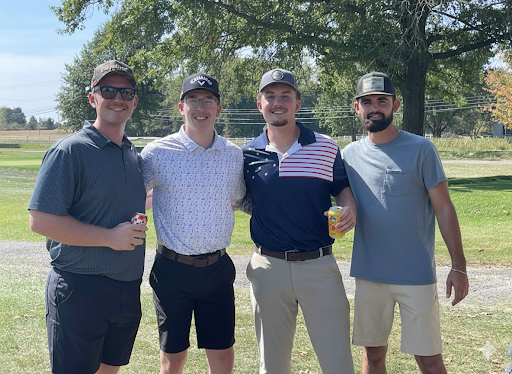 Four golfers smiling together at the annual company outing.